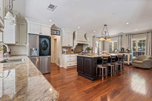 kitchen featuring visible vents, custom exhaust hood, a sink, and dark wood-type flooring