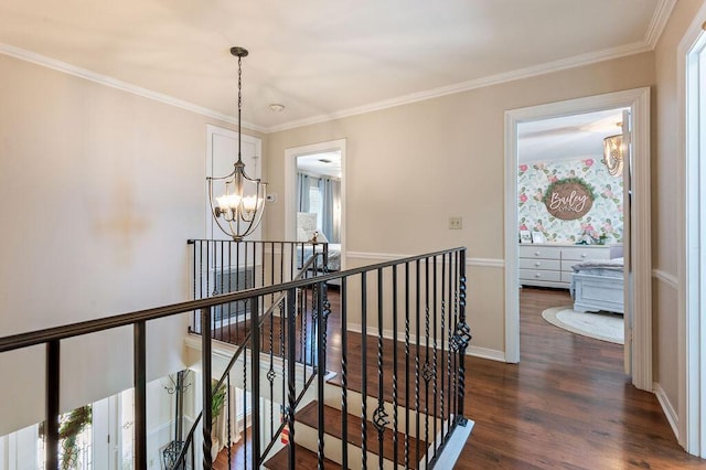 hall featuring crown molding, dark wood-style flooring, a notable chandelier, and an upstairs landing