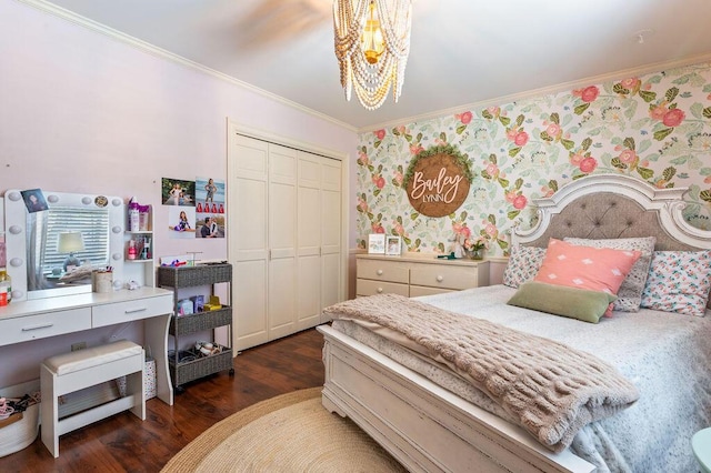 bedroom featuring wood finished floors, a closet, a notable chandelier, ornamental molding, and wallpapered walls