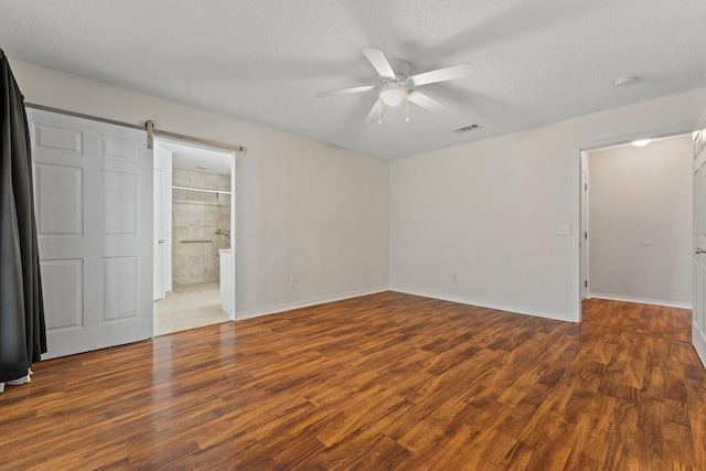 unfurnished bedroom featuring wood finished floors, ceiling fan, baseboards, visible vents, and a textured ceiling