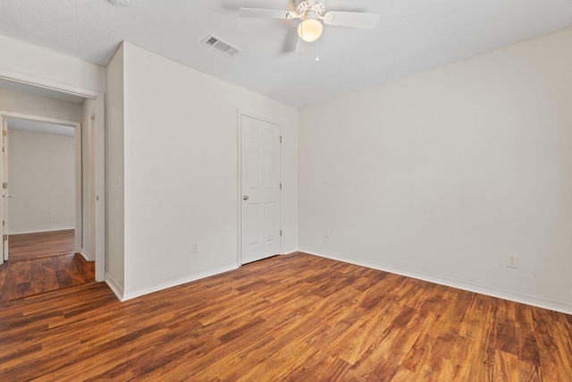 empty room with visible vents, ceiling fan, wood finished floors, and baseboards