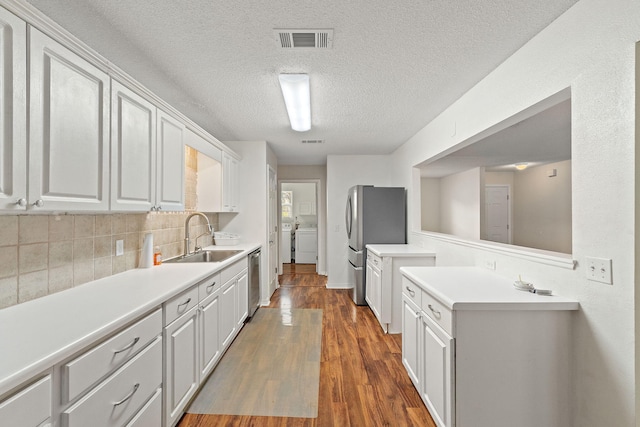 kitchen featuring a sink, stainless steel appliances, separate washer and dryer, light countertops, and a textured ceiling