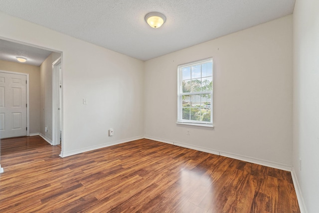 unfurnished room featuring a textured ceiling, wood finished floors, and baseboards