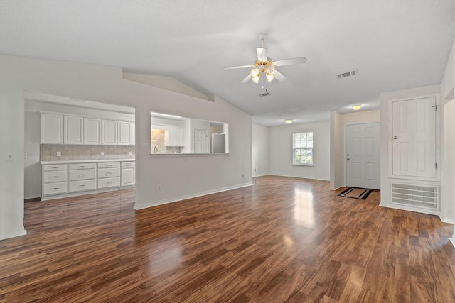unfurnished living room featuring dark wood finished floors, vaulted ceiling, baseboards, visible vents, and a ceiling fan