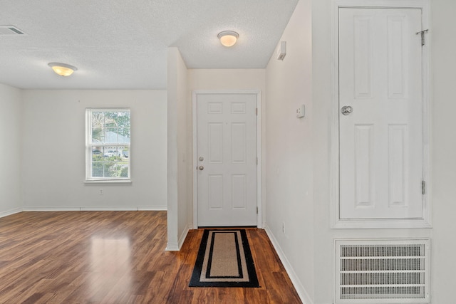entryway with baseboards, visible vents, wood finished floors, and a textured ceiling