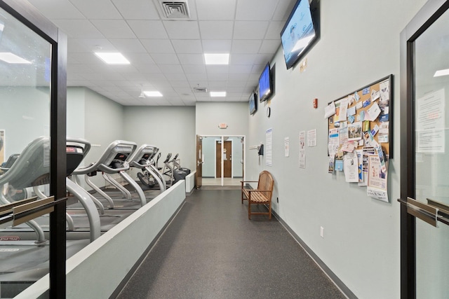 gym with baseboards, visible vents, and a drop ceiling
