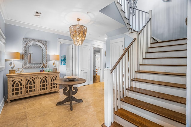 foyer entrance with a notable chandelier, stairs, visible vents, baseboards, and ornamental molding