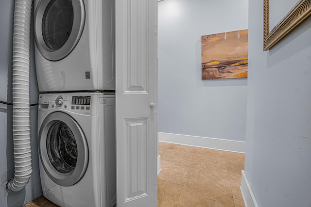 laundry area with light tile patterned floors, stacked washer and clothes dryer, laundry area, and baseboards