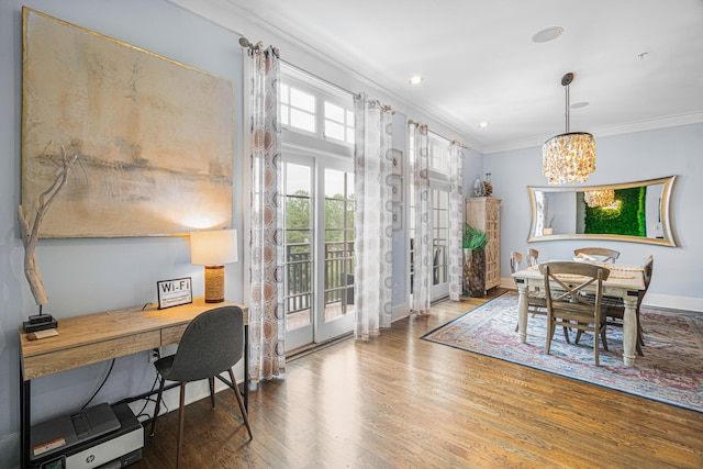 dining room with baseboards, ornamental molding, a notable chandelier, and wood finished floors
