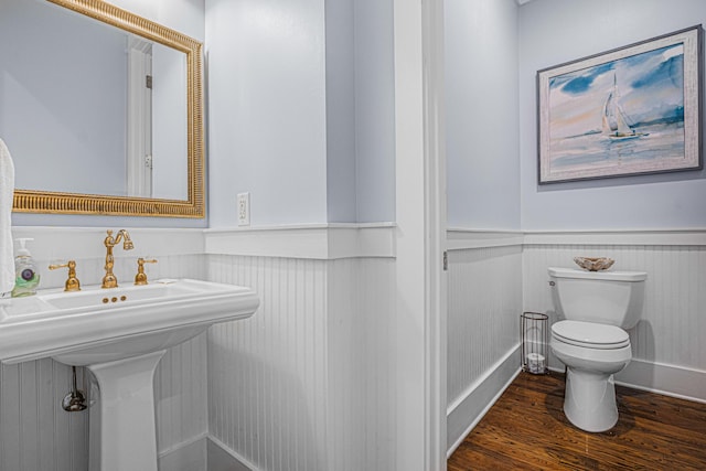 bathroom with wood finished floors, toilet, and wainscoting