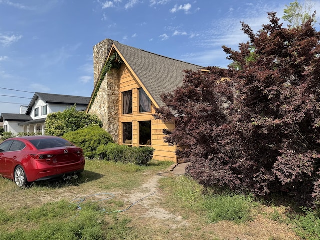 view of property exterior with stone siding and a shingled roof