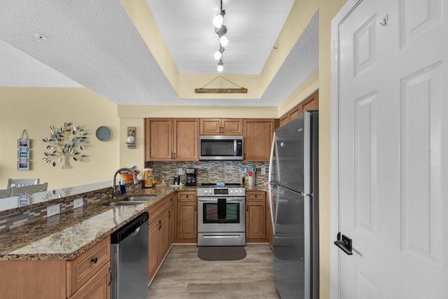 1160 Scenic Gulf Dr Unit 204A, Miramar Beach, FL 32550 - kitchen featuring a peninsula, light wood-type flooring, brown cabinets, a sink, and appliances with stainless steel finishes