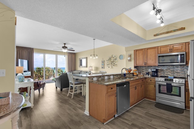 1160 Scenic Gulf Dr Unit 204A, Miramar Beach, FL 32550 - kitchen with brown cabinets, a sink, a peninsula, open floor plan, and stainless steel appliances