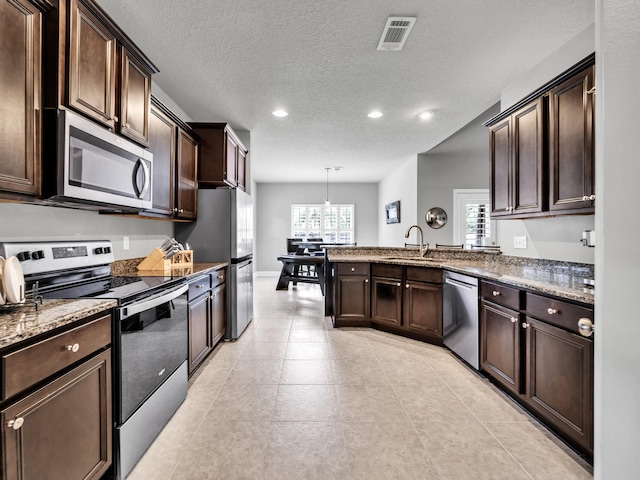 kitchen with dark brown cabinetry, recessed lighting, stainless steel appliances, a sink, and visible vents