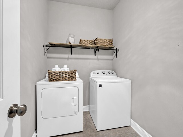 washroom with washer and clothes dryer, baseboards, light tile patterned floors, and laundry area