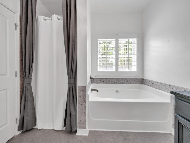 full bathroom featuring a garden tub, tile patterned floors, and vanity