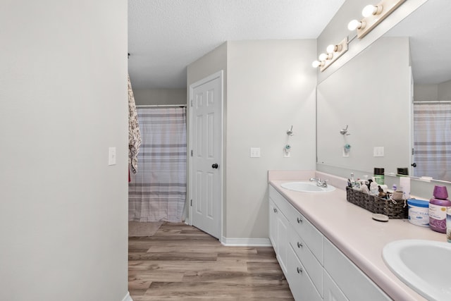 1207 Jefferyscot Dr, Crestview, FL 32536 - bathroom featuring wood finished floors, a textured ceiling, double vanity, and a sink