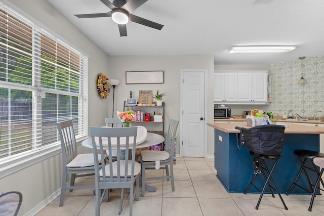 1207 Jefferyscot Dr, Crestview, FL 32536 - kitchen featuring light tile patterned floors, white cabinets, a breakfast bar, wooden counters, and a ceiling fan