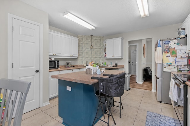 1207 Jefferyscot Dr, Crestview, FL 32536 - kitchen featuring electric stove, a breakfast bar area, light tile patterned floors, white cabinetry, and a center island