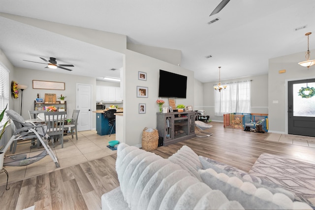 1207 Jefferyscot Dr, Crestview, FL 32536 - living area with lofted ceiling, visible vents, baseboards, light wood-type flooring, and ceiling fan with notable chandelier