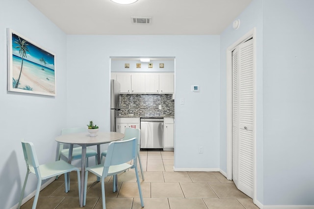 kitchen with light tile patterned floors, white cabinets, visible vents, stainless steel appliances, and backsplash