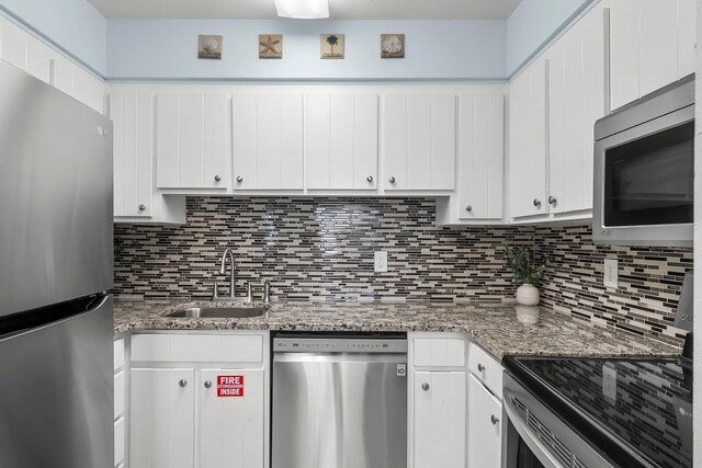 kitchen with a sink, white cabinetry, stainless steel appliances, and tasteful backsplash