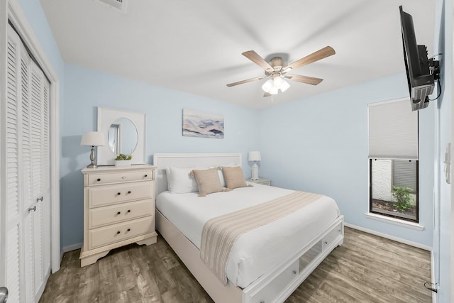 bedroom with baseboards, wood finished floors, ceiling fan, and a closet