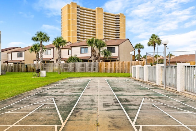 view of community with shuffleboard, fence, and a lawn