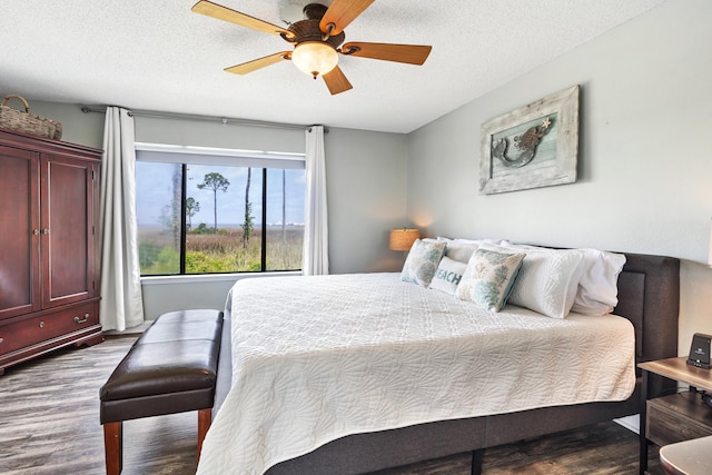 bedroom featuring a textured ceiling, ceiling fan, and dark wood finished floors