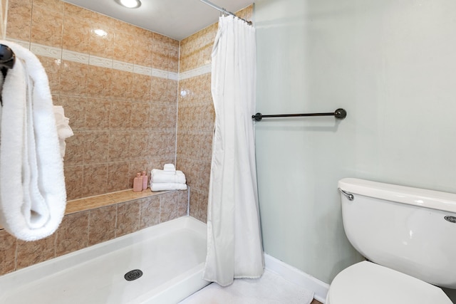 full bathroom with toilet, a shower stall, and baseboards