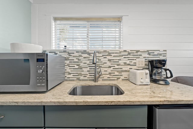kitchen with gray cabinets, tasteful backsplash, refrigerator, stainless steel microwave, and a sink