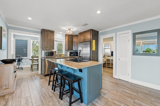 kitchen with crown molding, a kitchen breakfast bar, visible vents, and stainless steel appliances