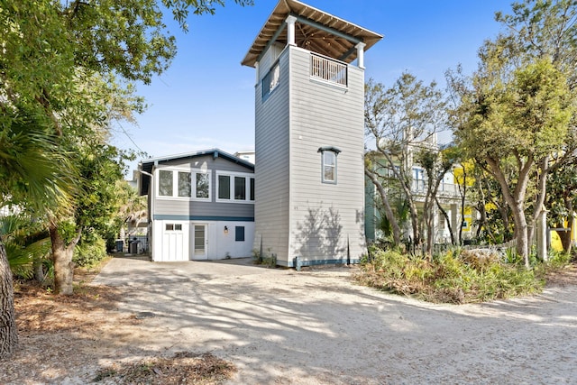 view of property exterior with dirt driveway and a balcony