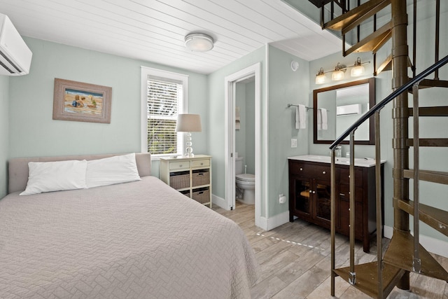 bedroom with wood finished floors and a wall mounted air conditioner