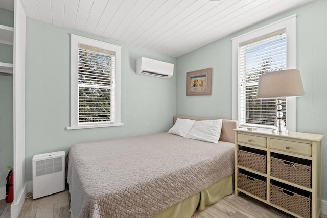 bedroom featuring a wall mounted air conditioner, wood finished floors, and wood ceiling