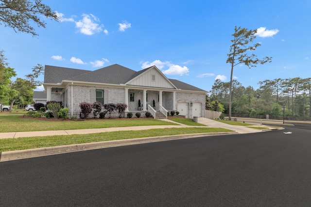 view of front of property featuring a porch, a front lawn, an attached garage, and driveway