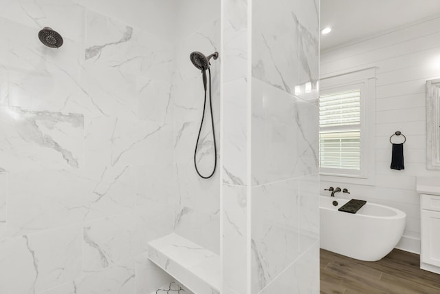 full bath with a freestanding bath, a marble finish shower, vanity, and wood finished floors