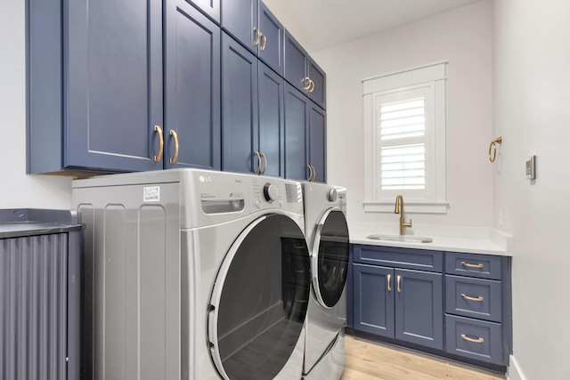 laundry area featuring a sink, light wood-style floors, independent washer and dryer, and cabinet space