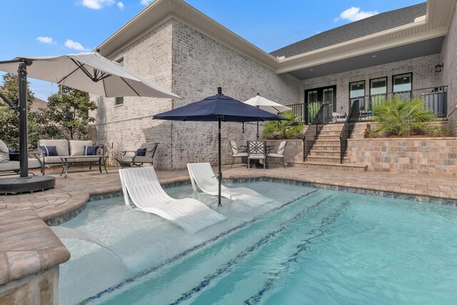 outdoor pool featuring stairs, an outdoor living space, and a patio area