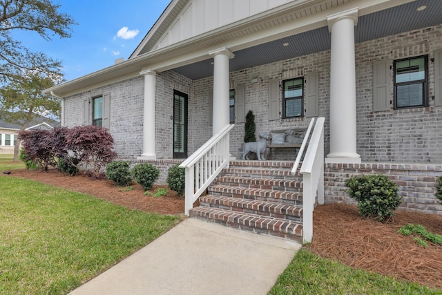 entrance to property featuring brick siding, board and batten siding, and covered porch