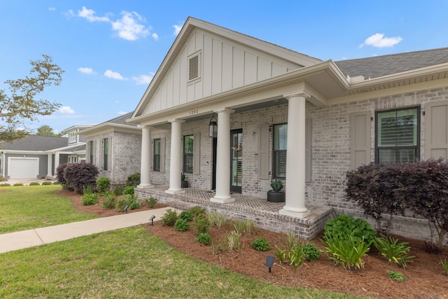 entrance to property with covered porch, board and batten siding, a yard, and brick siding