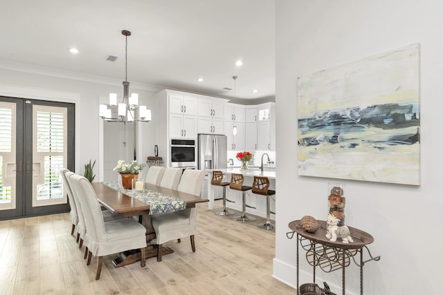 dining space featuring a chandelier, french doors, visible vents, and light wood-style floors