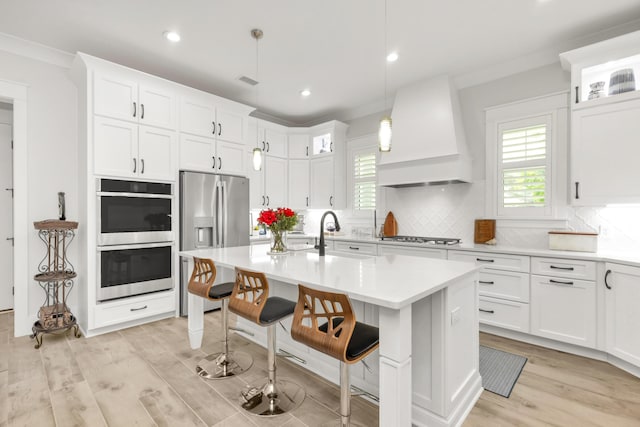 kitchen with light countertops, a kitchen breakfast bar, wall chimney exhaust hood, stainless steel appliances, and decorative backsplash