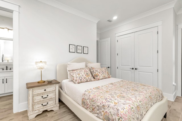 bedroom featuring crown molding, a closet, light wood finished floors, and a sink