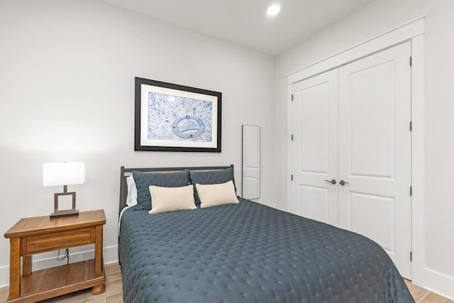 bedroom with recessed lighting, baseboards, light wood-type flooring, and a closet