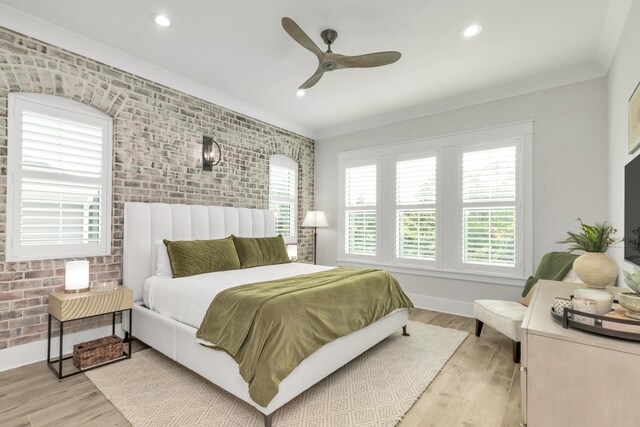 bedroom featuring brick wall, ornamental molding, baseboards, and light wood-style floors