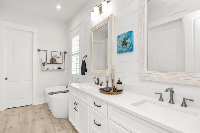 full bath featuring a sink, a soaking tub, recessed lighting, and double vanity