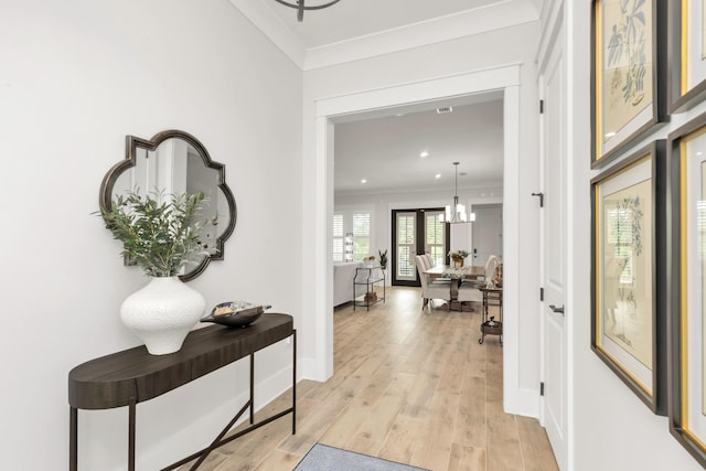 hallway featuring crown molding, baseboards, light wood finished floors, a chandelier, and recessed lighting