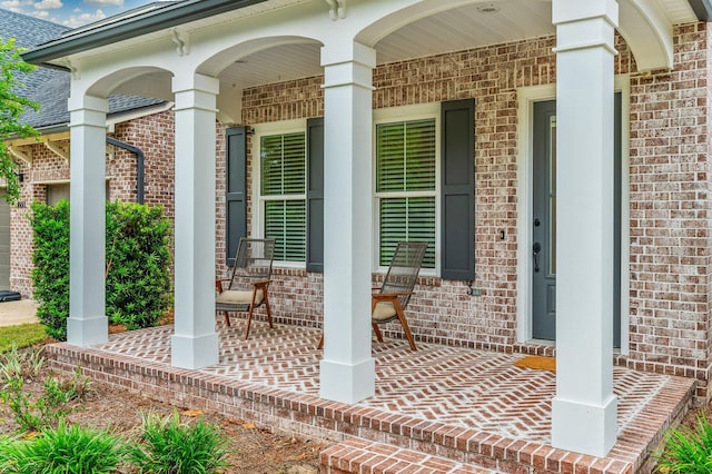 entrance to property featuring covered porch and brick siding