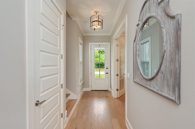 entryway featuring baseboards, ornamental molding, and light wood finished floors
